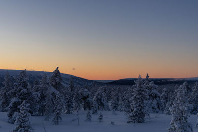 Snow covered landscape against clear sky during sunset