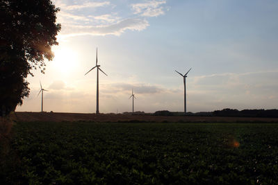 Windmill on field against sky during sunset