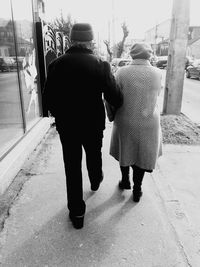 Full length rear view of woman standing against white wall