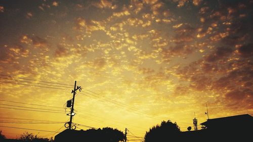 Low angle view of silhouette electricity pylon against sky during sunset