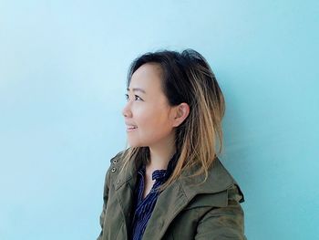 Smiling young woman standing against blue wall