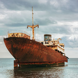 Abandoned ship in sea against sky