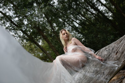 Full length of woman with arms raised against trees