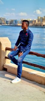 Young man sitting on retaining wall