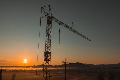 Silhouette crane against clear sky during sunset