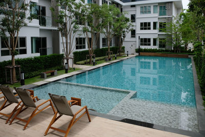 Chairs by swimming pool against buildings