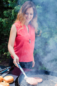 Young woman standing on barbecue grill