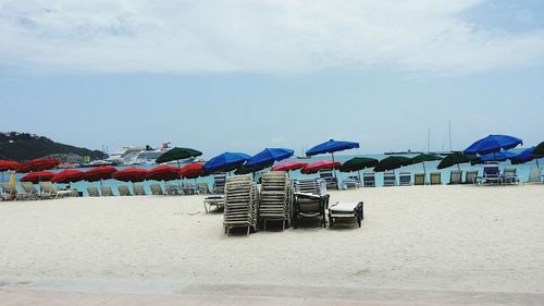 Lounge chairs on beach against sky