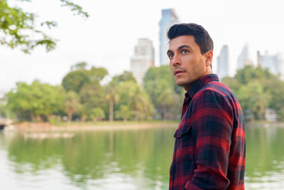 Portrait of young man standing by lake