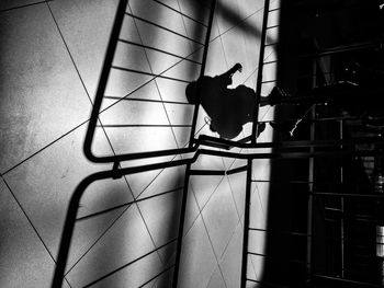 High angle view of silhouette woman walking on tiled floor