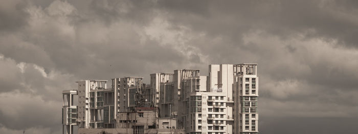 Low angle view of buildings against dramatic cloudy sky