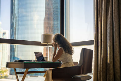 Rear view of woman looking through window