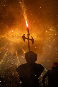 Rear view of two people with fire crackers at night