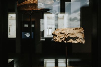 Close-up of glass on table against illuminated wall