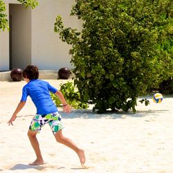 Rear view of boy playing on sand at beach