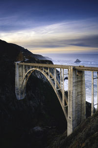 Arch bridge over sea against sky during sunset