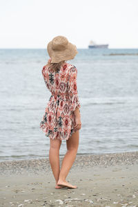 Rear view of woman standing at beach