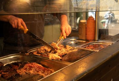 Cropped hand preparing food on barbecue grill
