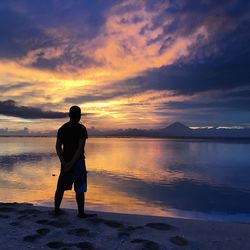 Rear view of man standing against sea during sunset