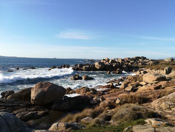 Rocks by sea against blue sky