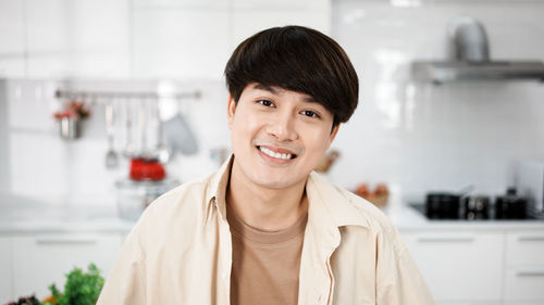 Portrait of handsome gay, attractive young gay smile in kitchen room.