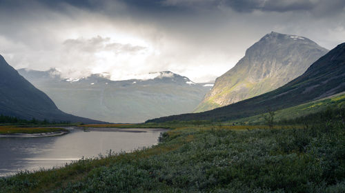 Scenic view of mountains and lake against cloudy sky