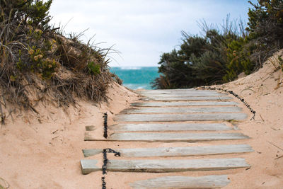 Footpath by sea against sky