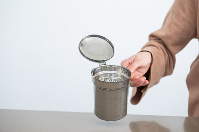 Midsection of person holding wineglass against white background