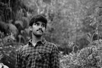 Young man standing against plants