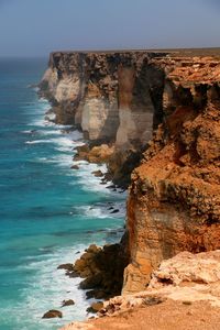 Rock formations by sea against clear sky