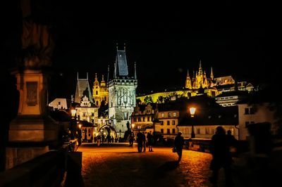 People at illuminated temple against sky at night