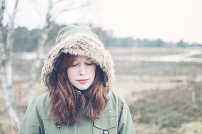 Thoughtful beautiful woman standing on field during winter