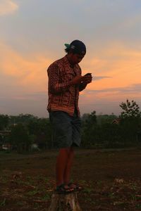 Man standing on field against sky during sunset