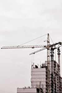 Cranes at construction site against sky