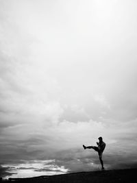 Silhouette man kicking on landscape against sky