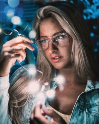 Portrait of young woman holding sunglasses