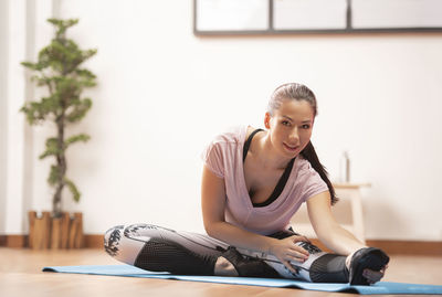 Full length portrait of woman doing yoga at home