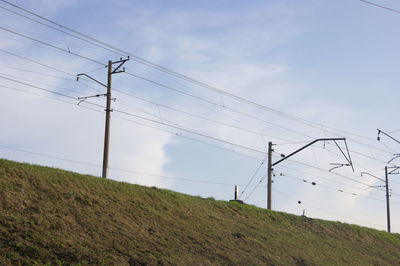 Low angle view of electricity pylon on field against sky