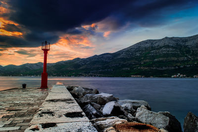 Lighthouse by sea against sky during sunset