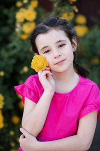 Stylish little kid girl 6-7 year old smell yellow rose flower bloom bushes in garden outdoor closeup
