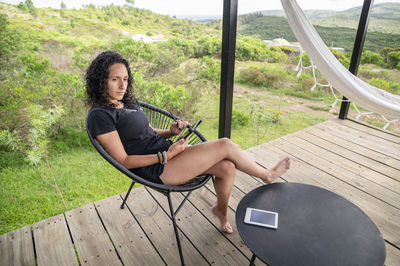 Woman using a digital tablet while relaxing sitting outdoors.