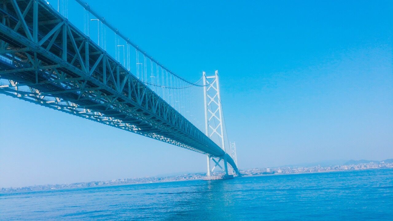 bridge - man made structure, transportation, connection, sea, outdoors, sky, built structure, blue, travel, clear sky, travel destinations, architecture, suspension bridge, day, no people, nature, water, city