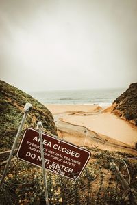 Information sign on beach against sky