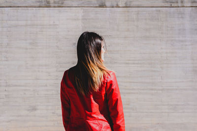 Rear view of woman standing against red wall