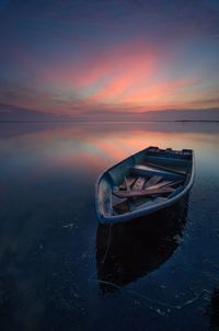 Boat moored on sea against sky during sunset