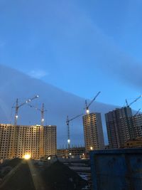 Low angle view of cranes at construction site against sky