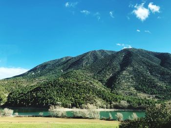 Scenic view of lake and mountains against blue sky