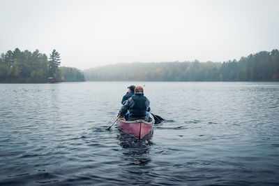 Rear view of man on boat in lake against sky