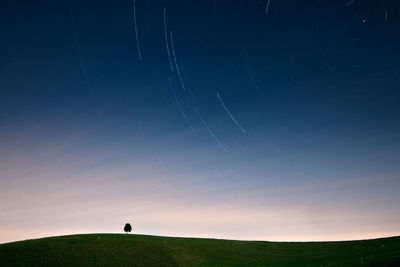Scenic view of field against star trails at night