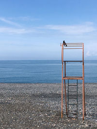 Lifeguard chair on beach against sky